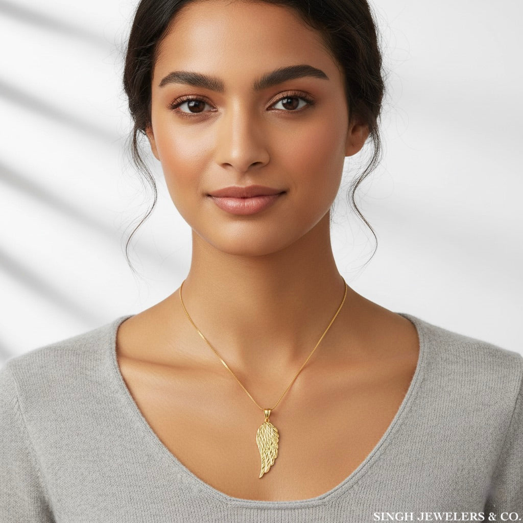 Woman wearing a gold necklace with a leaf pendant against a neutral background
