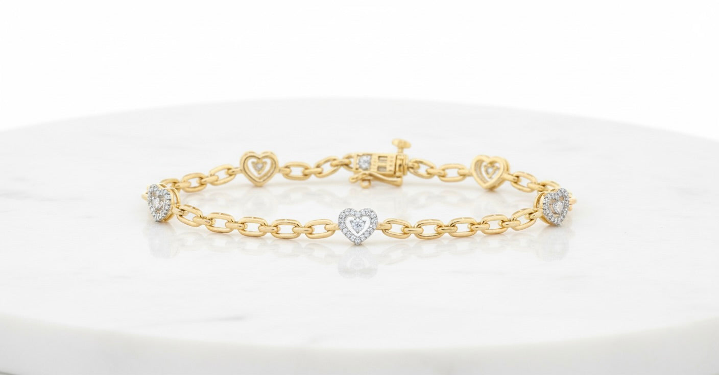 Gold bracelet with heart-shaped charms on a white marble surface
