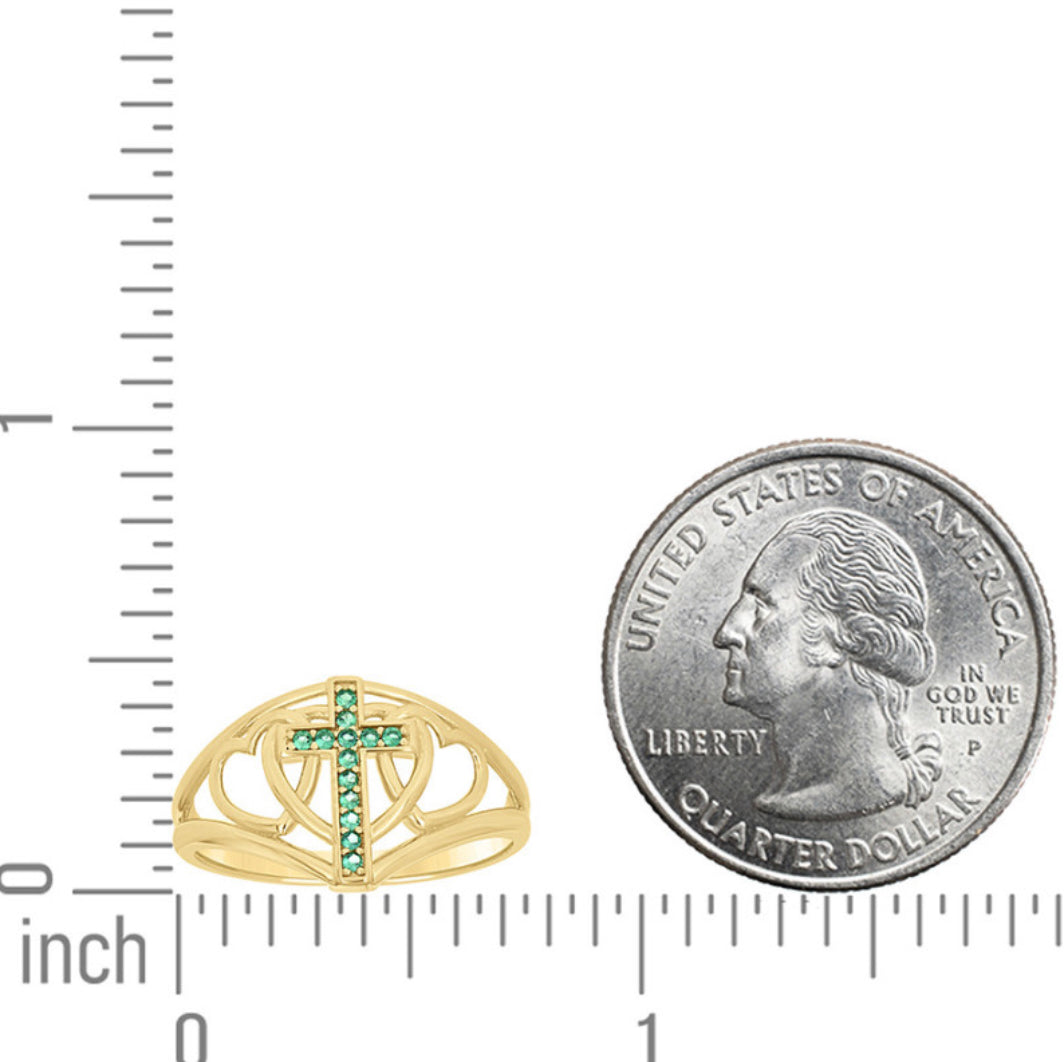 Gold ring with green gemstones next to a quarter for size comparison on a white background.
