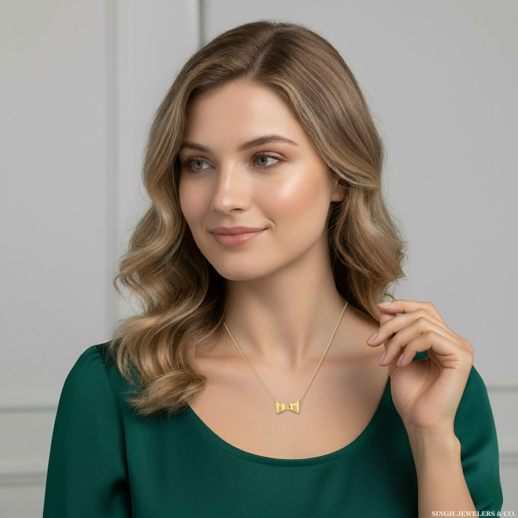 Woman wearing a gold necklace with a green top against a neutral background