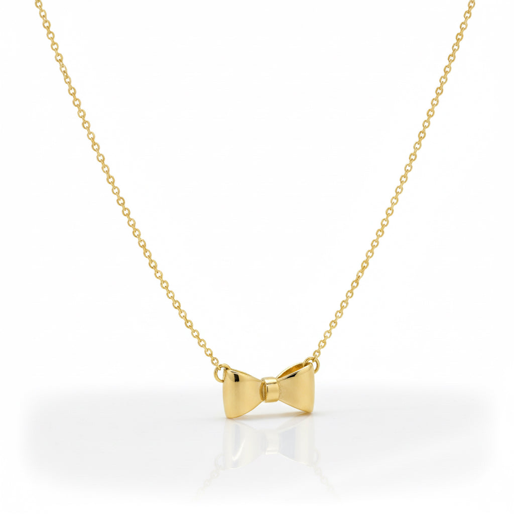 Gold bow-shaped pendant on a chain against a white background