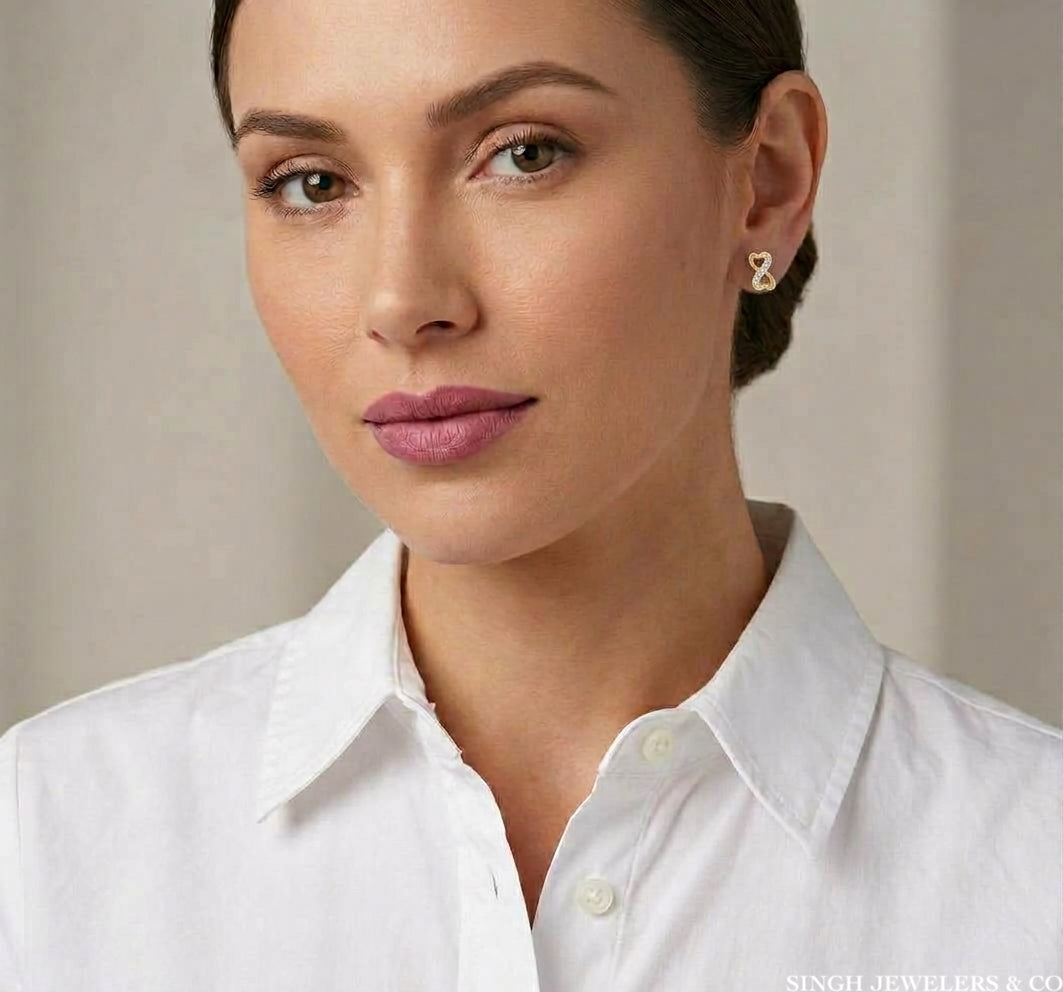 14K yellow gold cubic zirconia infinity heart stud earrings modeled on the ear