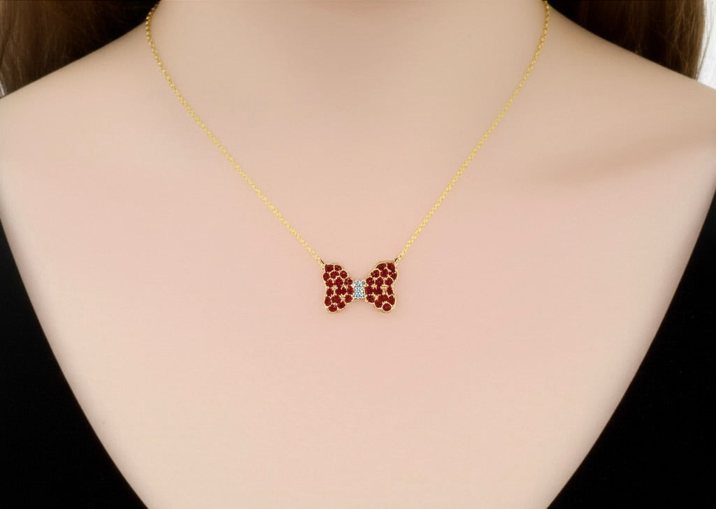 14K yellow gold natural diamond and ruby bow necklace worn on model, 18-inch length