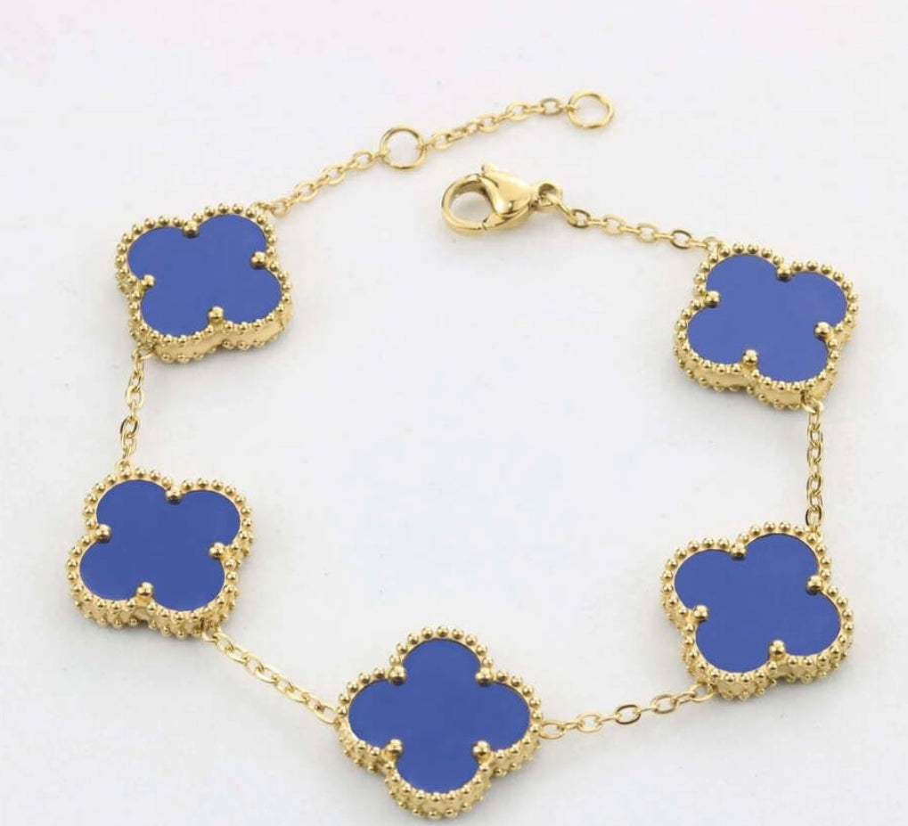 A 10K yellow gold bracelet with royal blue clover charms and a secure lobster closure.