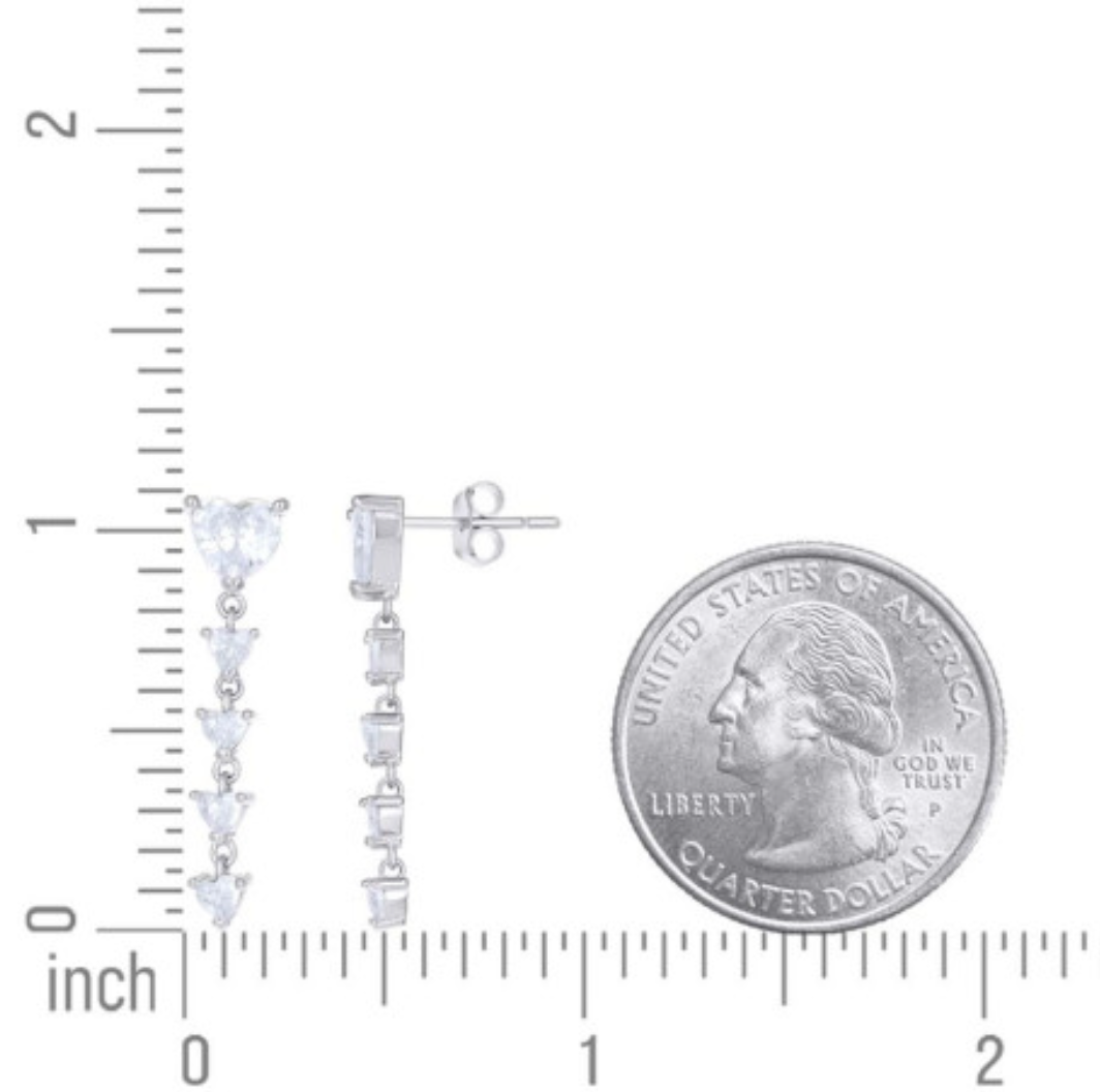 Pair of silver earrings with clear stones next to a quarter for size reference on a white background.