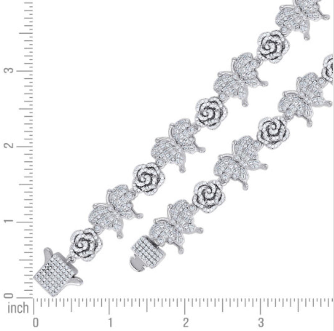 Silver bracelet with floral designs next to a ruler for size reference
