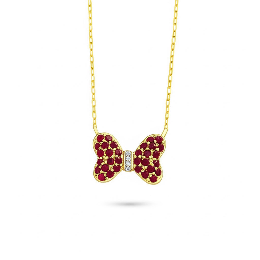 Close-up of 5/8 CTW round-cut diamond bow necklace with natural ruby gemstones set in 14K yellow gold