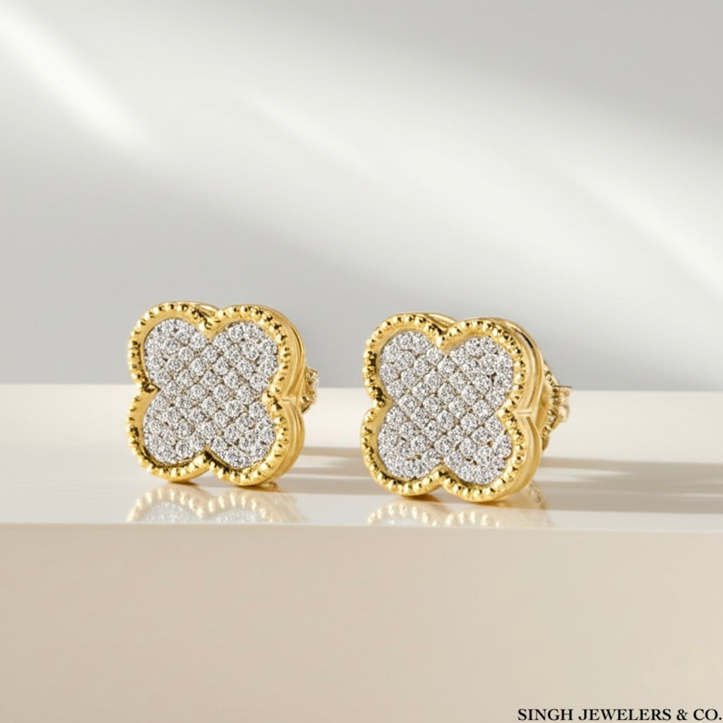 Gold and diamond earrings on a reflective surface with a neutral background