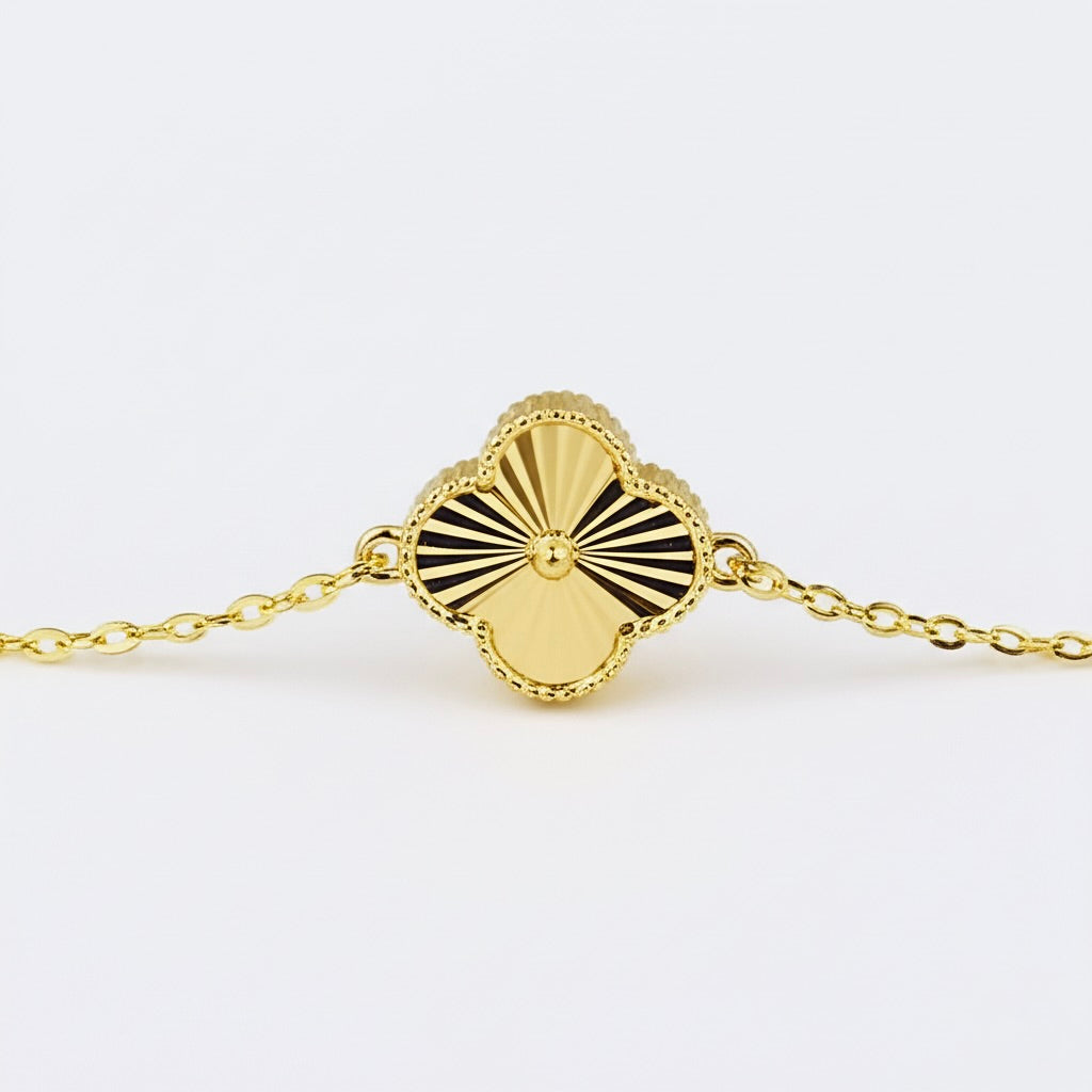 Close-up of gold clover motif charm on bracelet