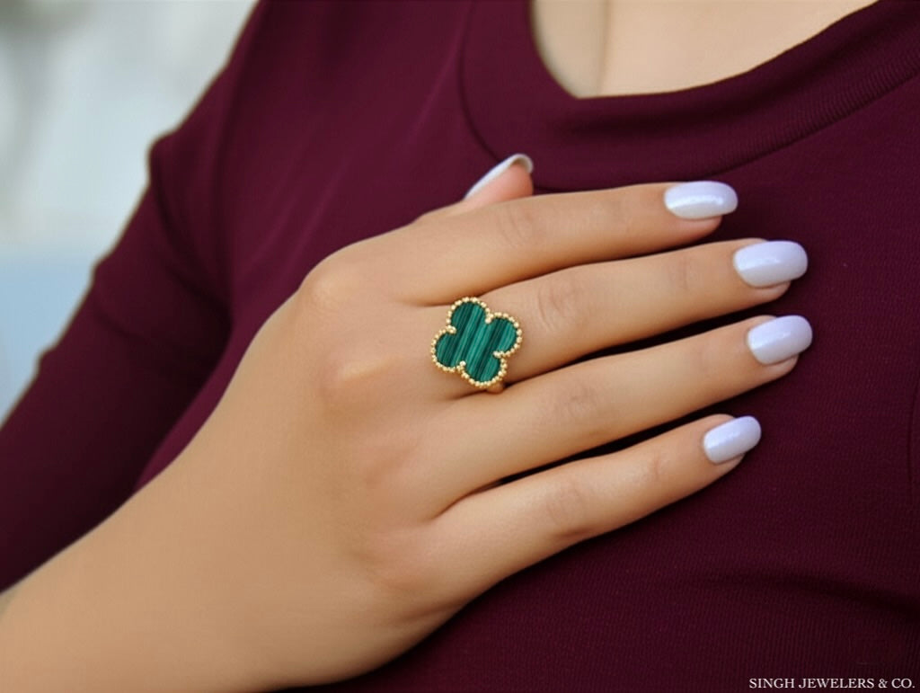 Gold ring with green gemstone on a hand against a blurred background