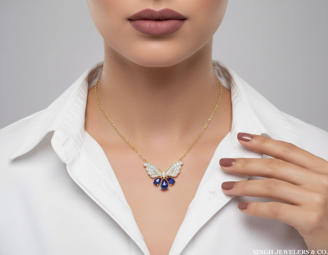Gold necklace with a blue gemstone worn by a person in a white shirt, with 'Singh Jewelers & Co.' branding.