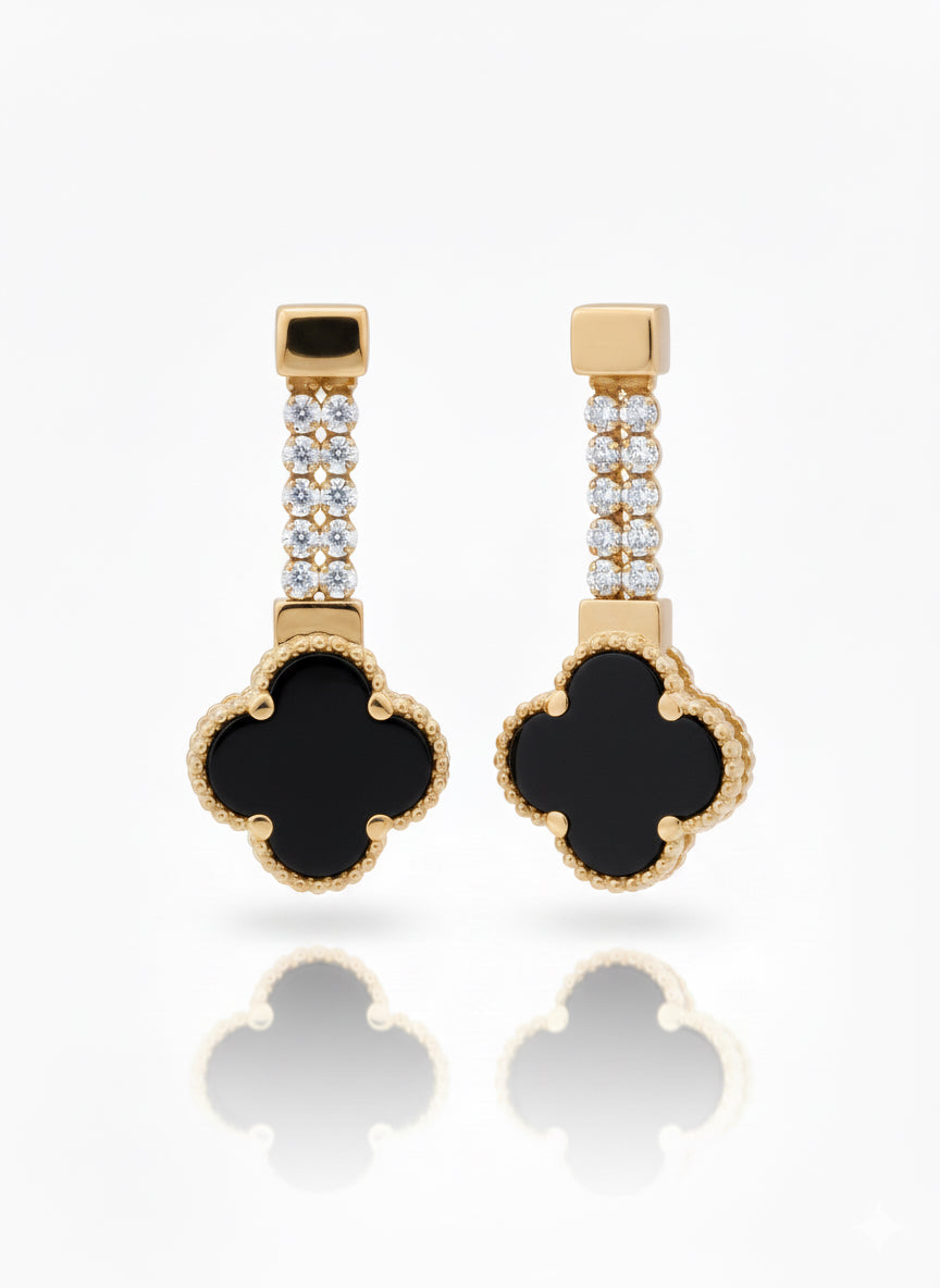 Pair of gold earrings with black clover-shaped drops on a white background