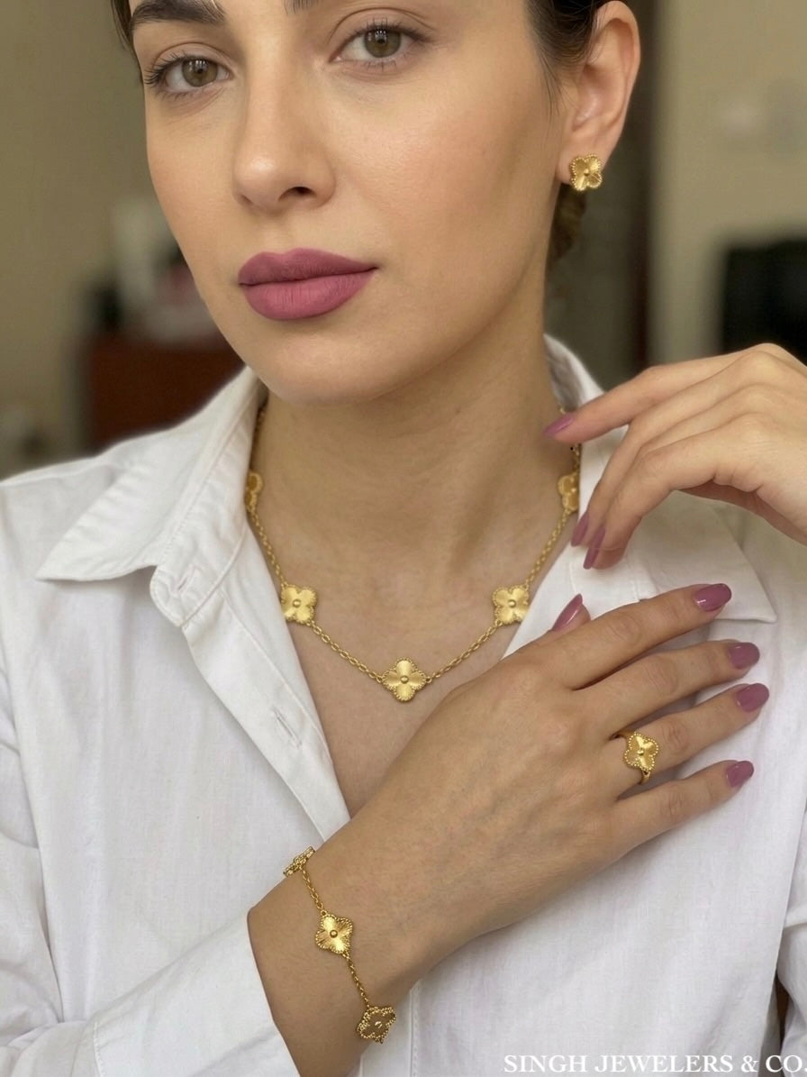 Woman wearing gold tone stainless steel clover jewelry set with matching necklace, bracelet, and earrings