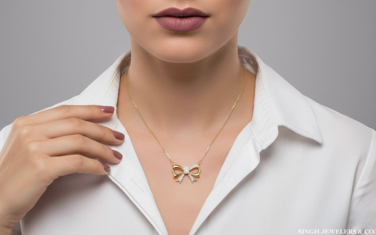 Woman wearing a gold bow-shaped necklace against a gray background