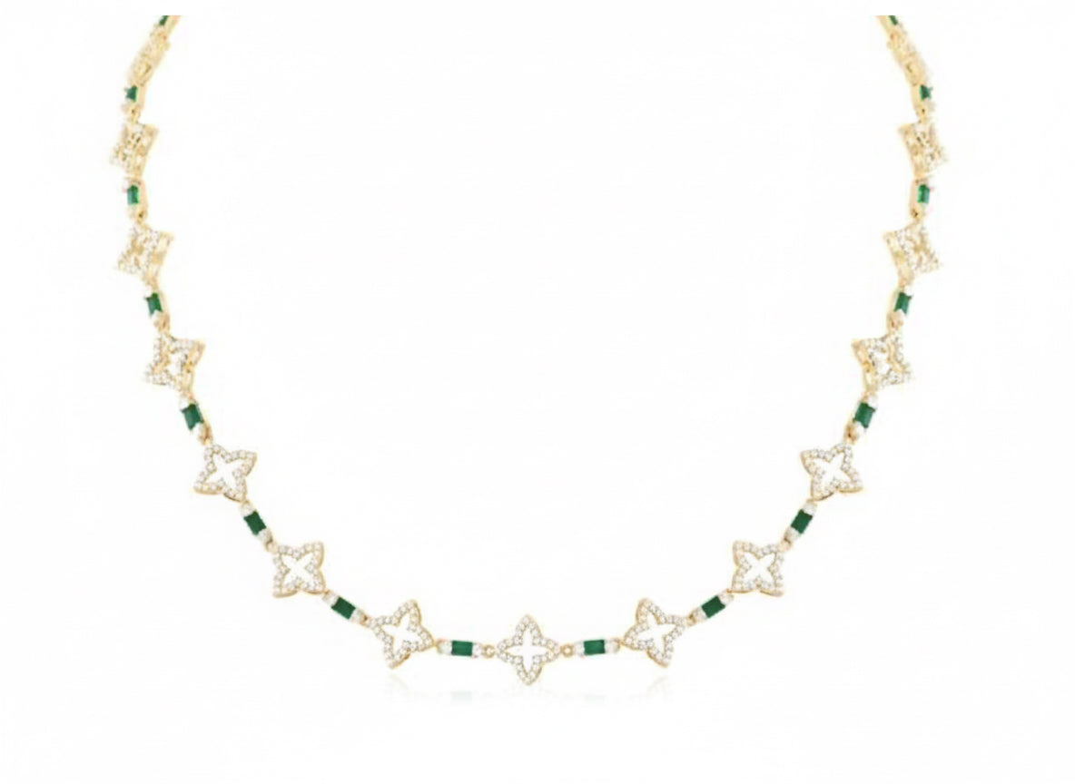 Gold necklace with green gemstones on a white background