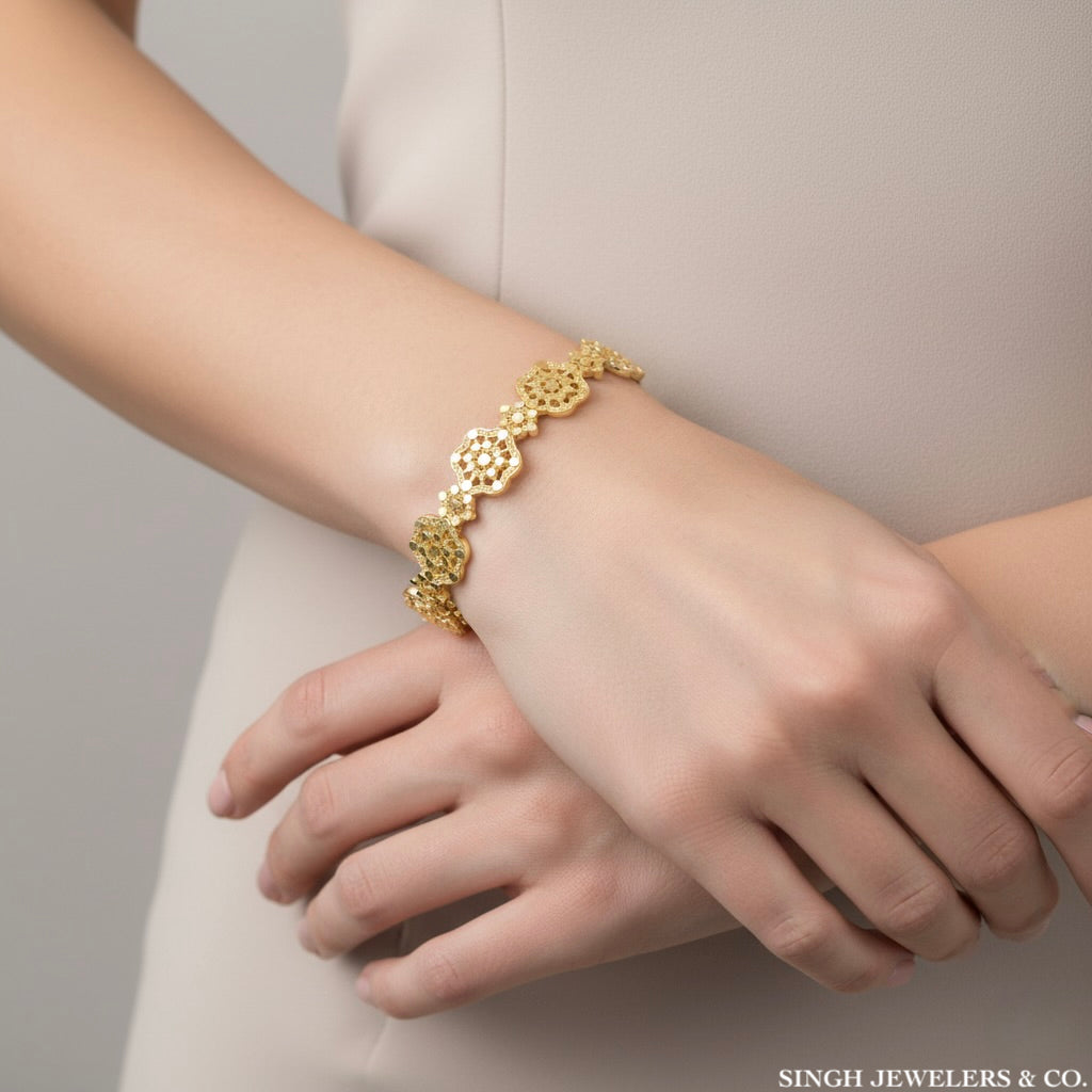 Gold bracelet on a person's wrist with a neutral background