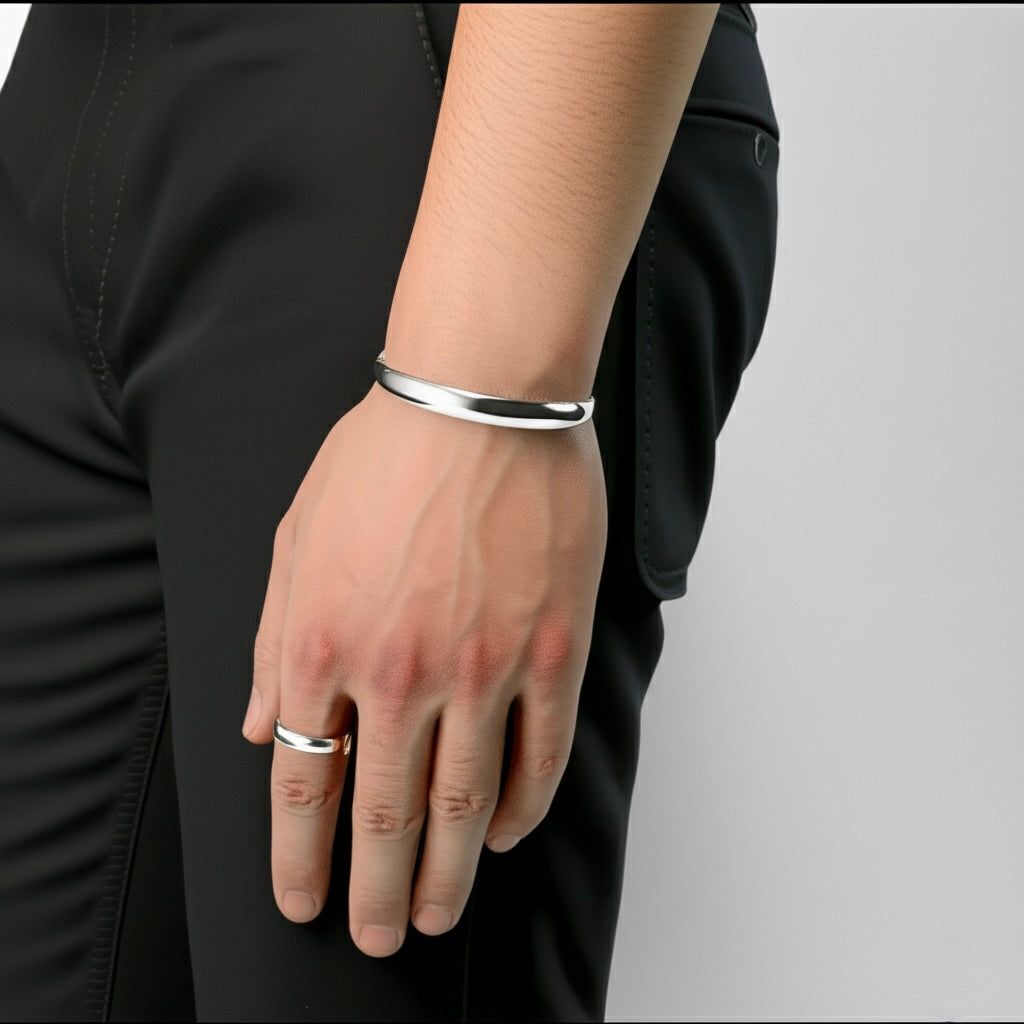 Silver bracelet and ring on a person's wrist against a black garment and gray background