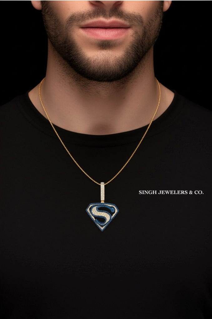 Man wearing a gold necklace with a Superman pendant against a black background, featuring 'Singh Jewelers & Co.'