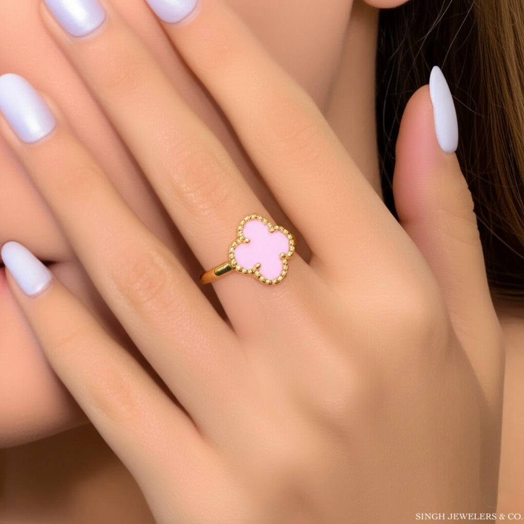Pink clover-shaped ring on a hand with white nail polish