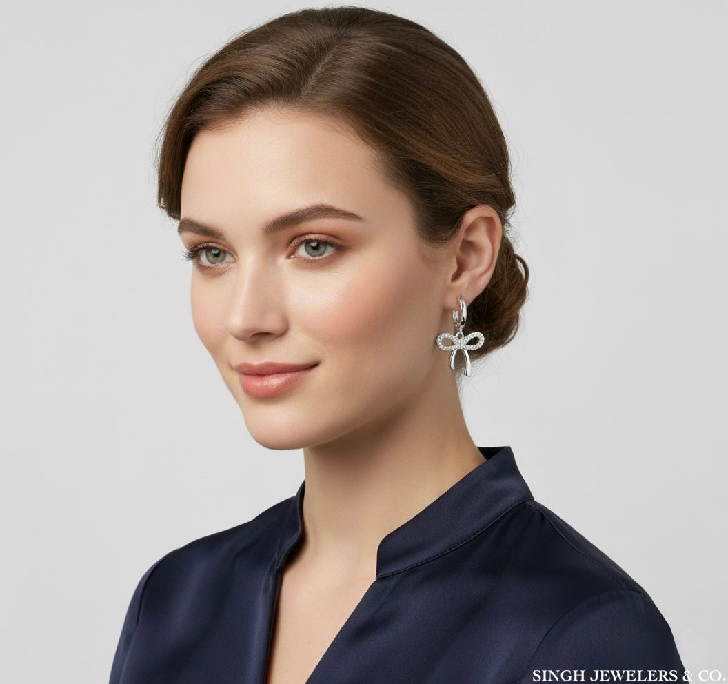 Woman wearing a silver bow earring with a neutral background