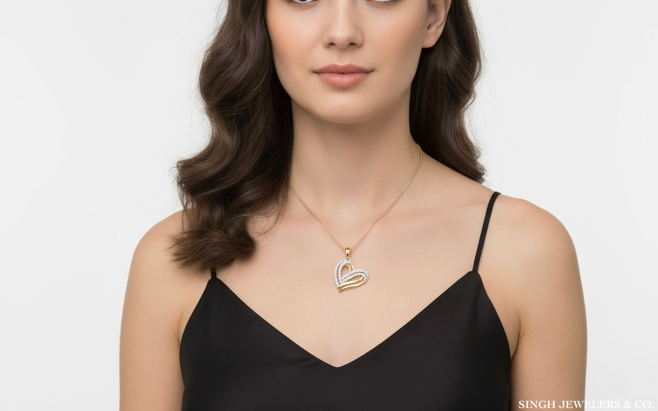 Woman wearing a black top and gold necklace with a heart pendant on a white background