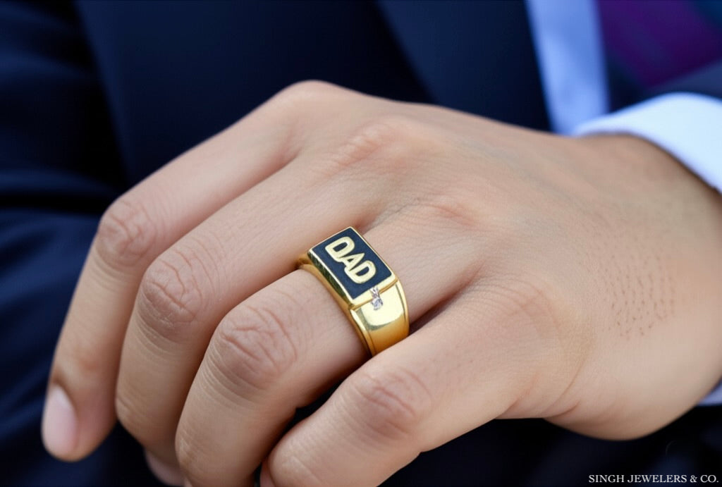 Gold ring with 'DAD' engraving on a person's finger, wearing a suit.