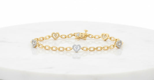 Gold bracelet with heart-shaped charms on a white marble surface