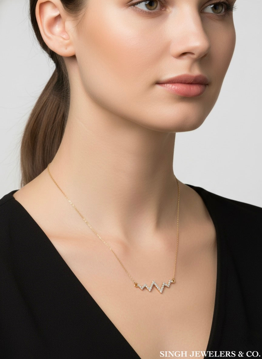 Woman wearing a gold necklace with a minimalistic design on a plain background, branded 'Singh Jewelers & Co'.