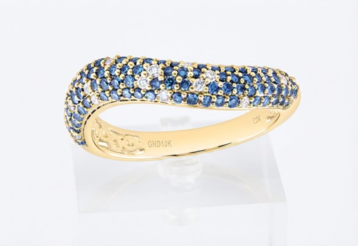 A yellow gold band ring set with rows of blue sapphires and small clear stones, displayed on a clear stand against a white background.