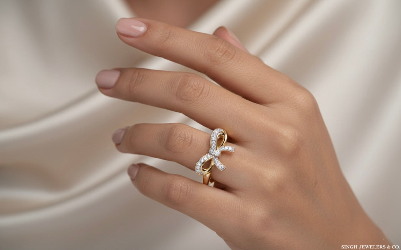 Hand wearing a gold bow-shaped ring on a soft beige background