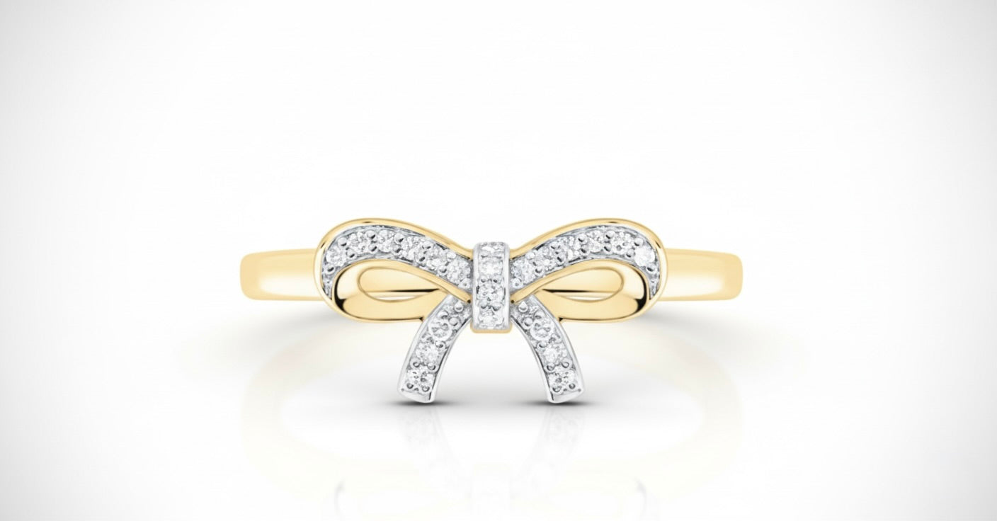 Gold bow-shaped ring with diamonds on a white background