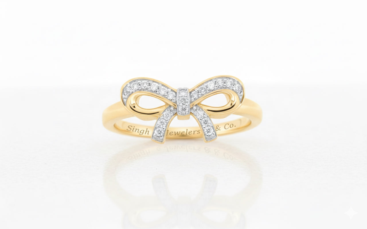 Gold bow-shaped ring with diamonds on a white background