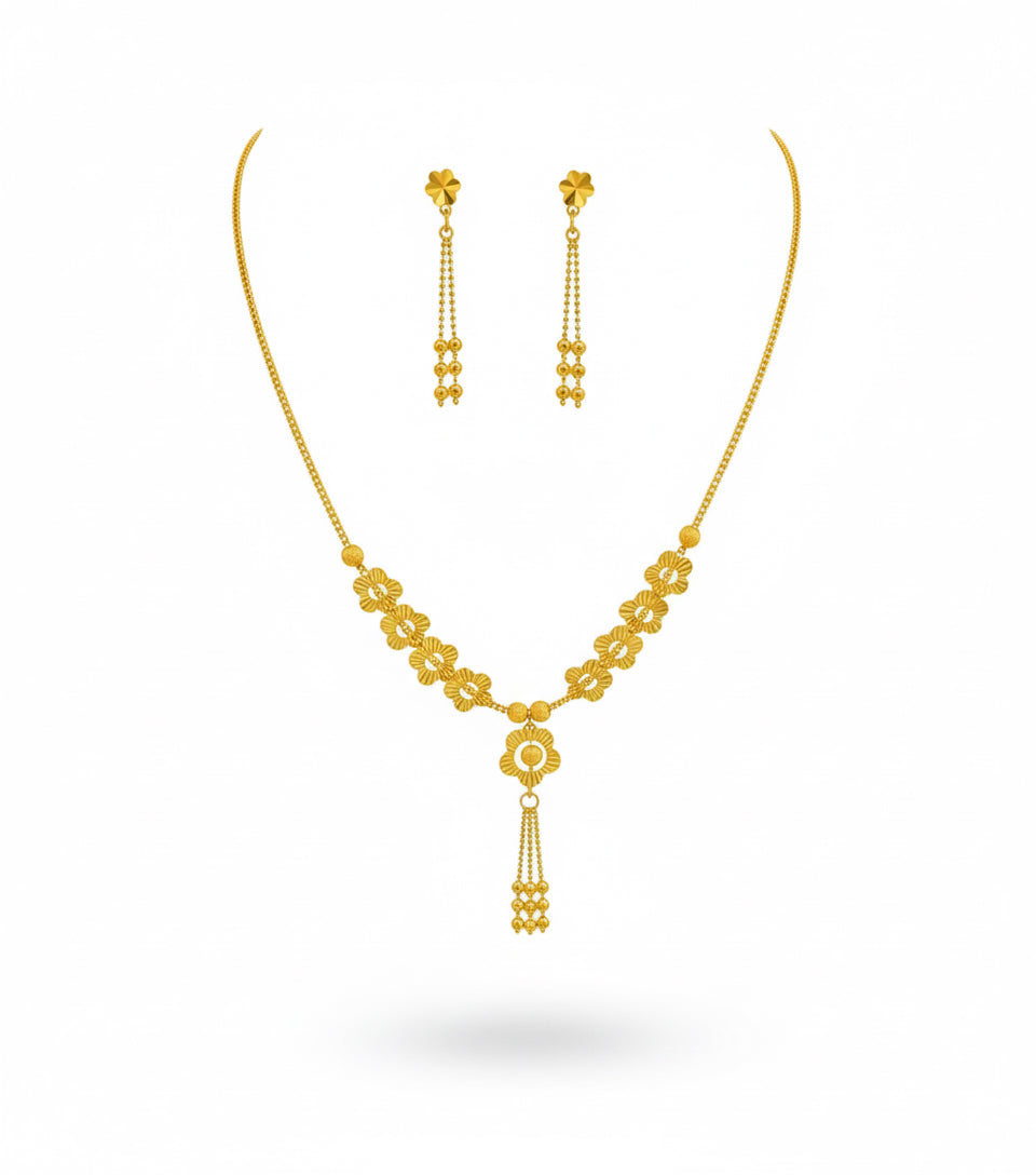 Gold necklace and earrings set on a white background