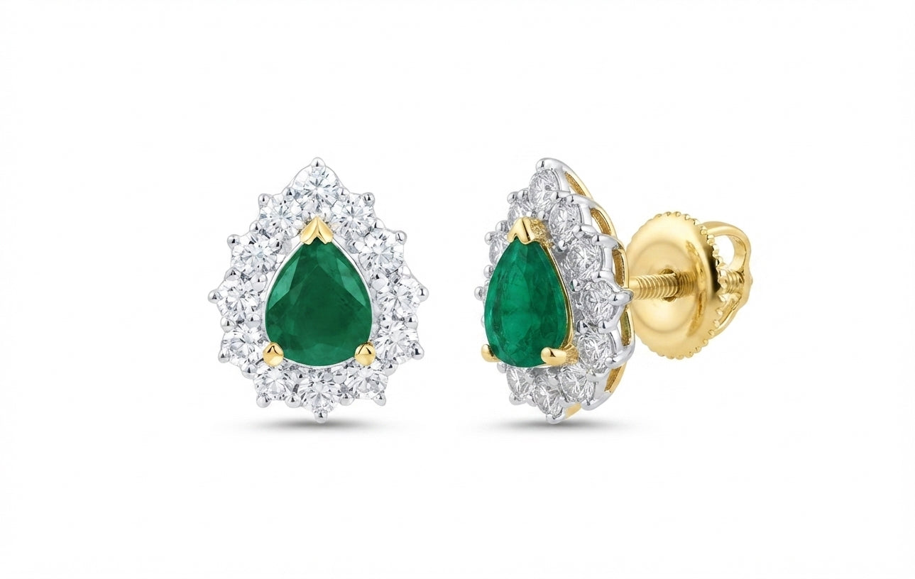 A pair of pear-cut emerald stud earrings in yellow gold with a halo of small clear stones and a central green emerald, shown on a plain white background. One earring is facing forward and the other is angled to show the post and backing.