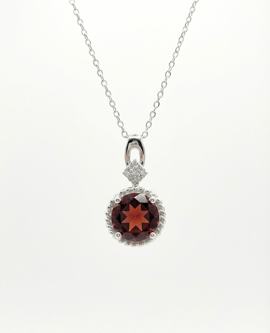 Silver necklace with a round pendant featuring a red gemstone on a white background