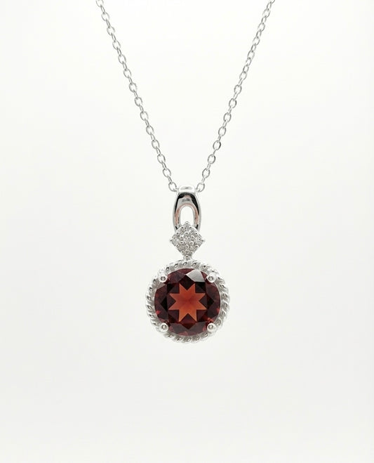 Silver necklace with a round pendant featuring a red gemstone on a white background