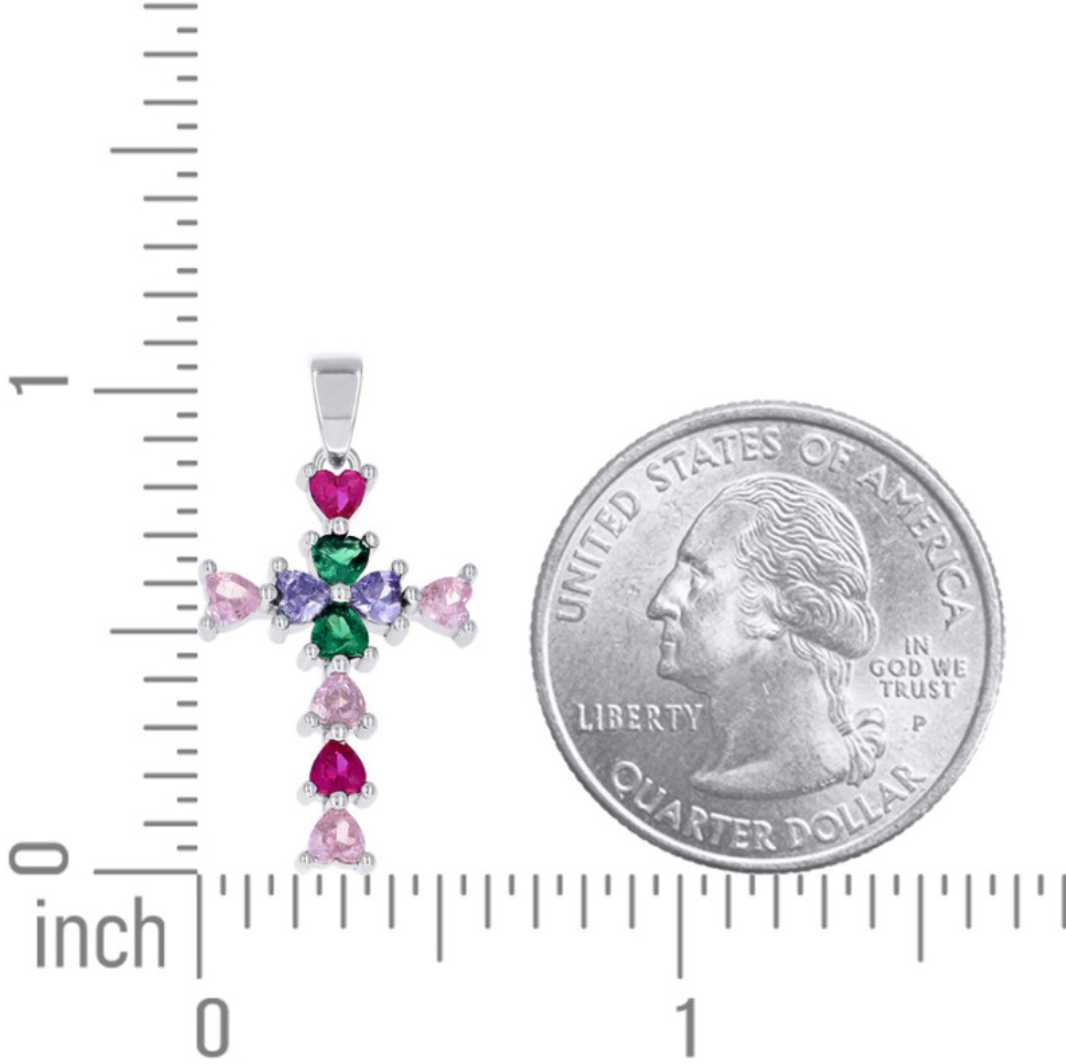 Colorful cross pendant with gemstones next to a quarter for scale on a white background