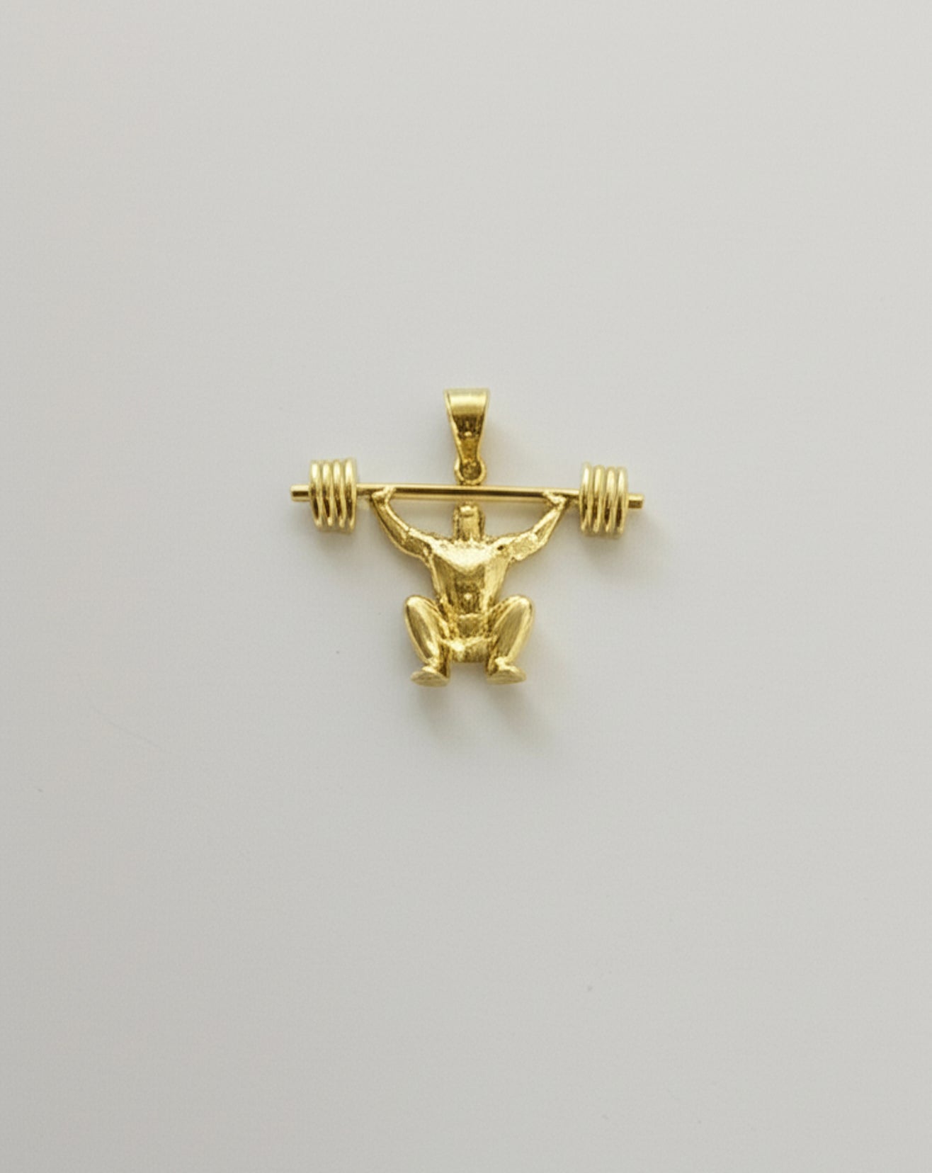 Close-up showing muscle detail on gold gym pendant