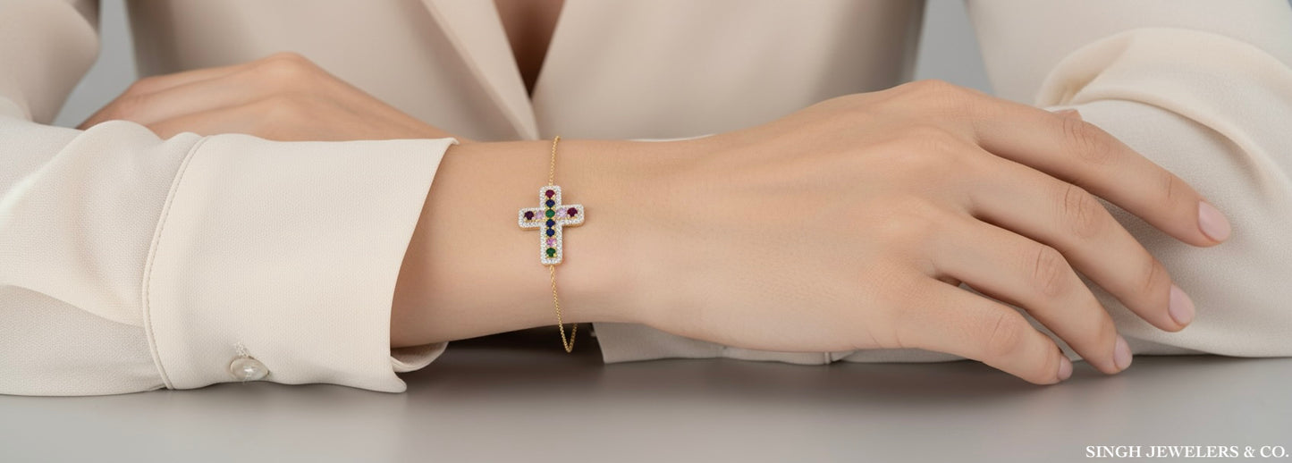 Silver bracelet with a cross design on a person's wrist, wearing a light-colored shirt.