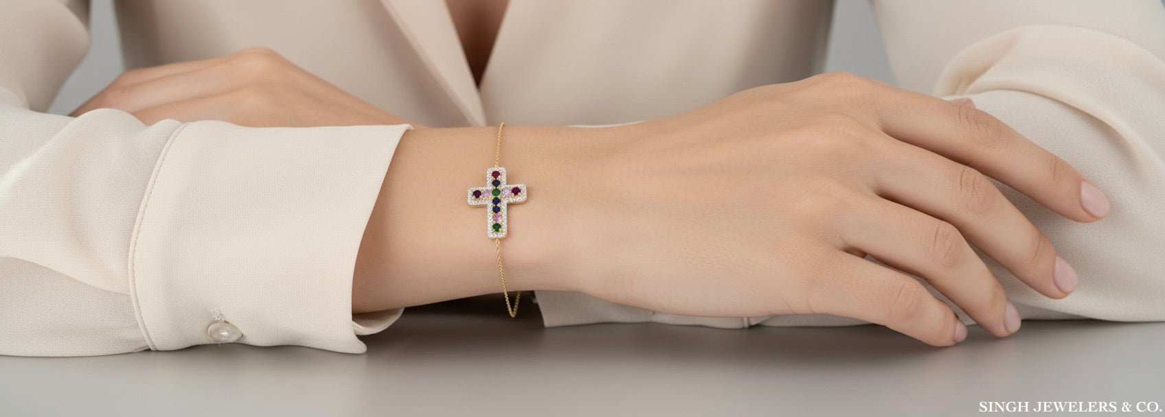 Silver bracelet with a cross design on a person's wrist, wearing a light-colored shirt.