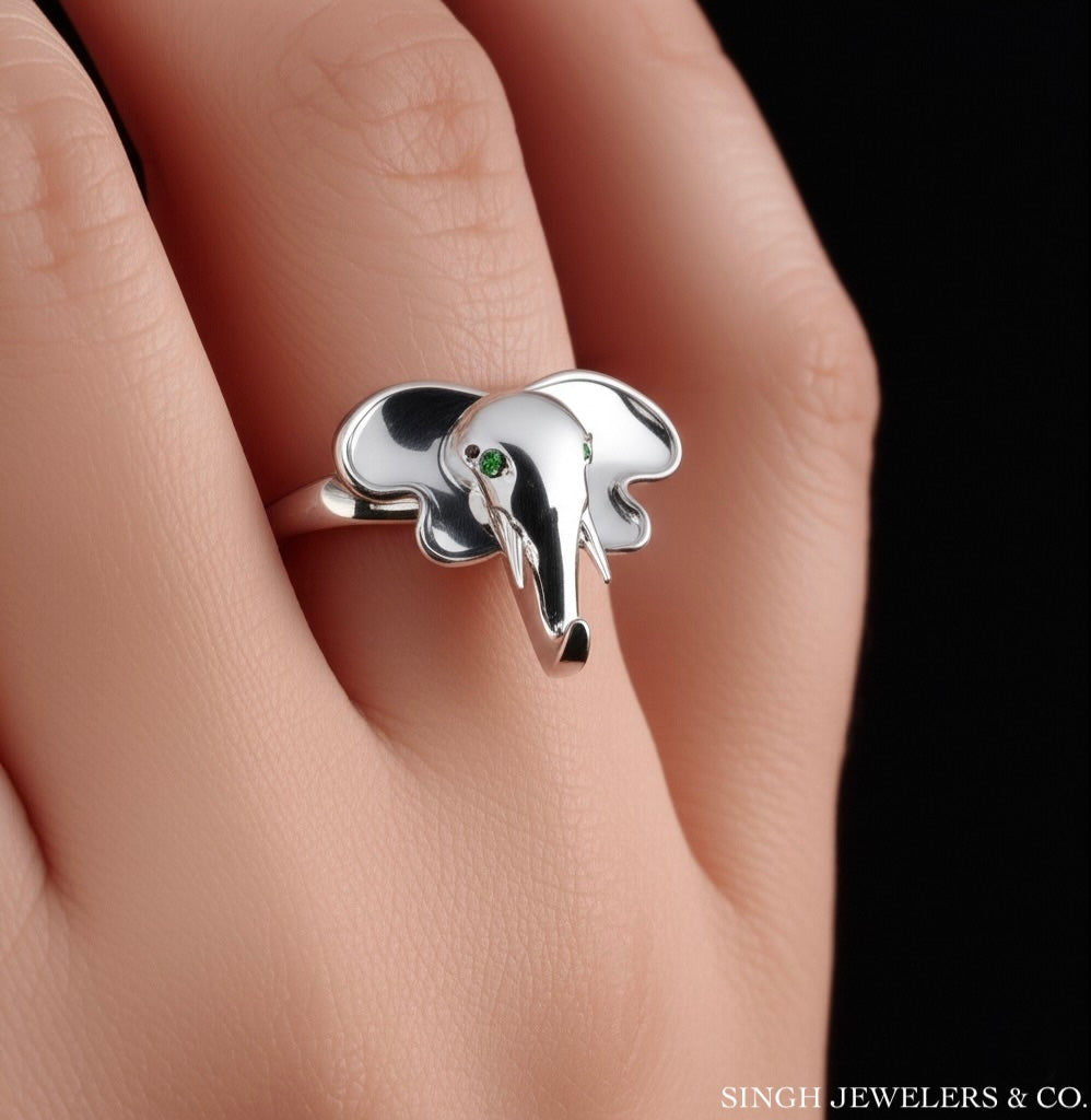 Emerald-accented elephant ring worn on model’s hand