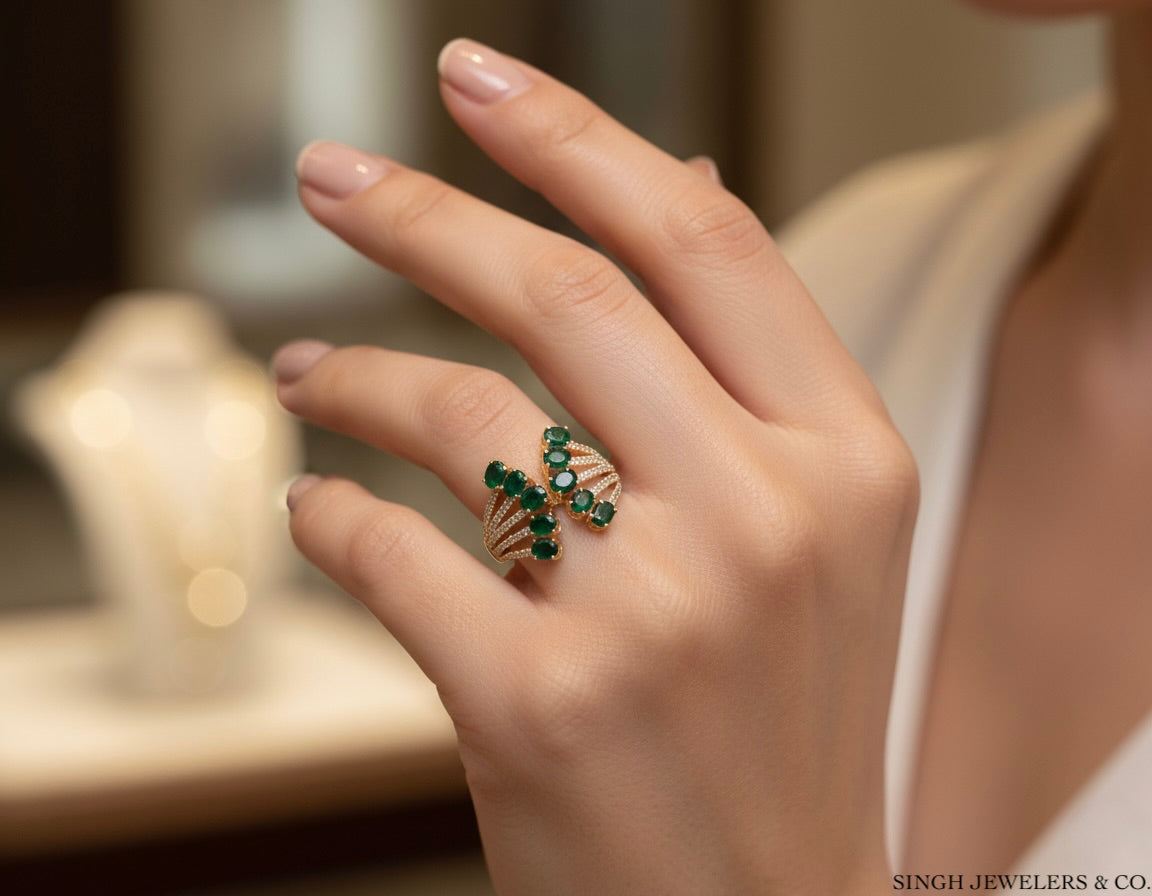 Hand wearing a green emerald ring with a blurred background