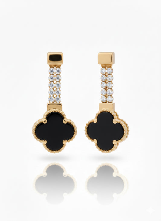 Pair of gold earrings with black clover-shaped drops on a white background