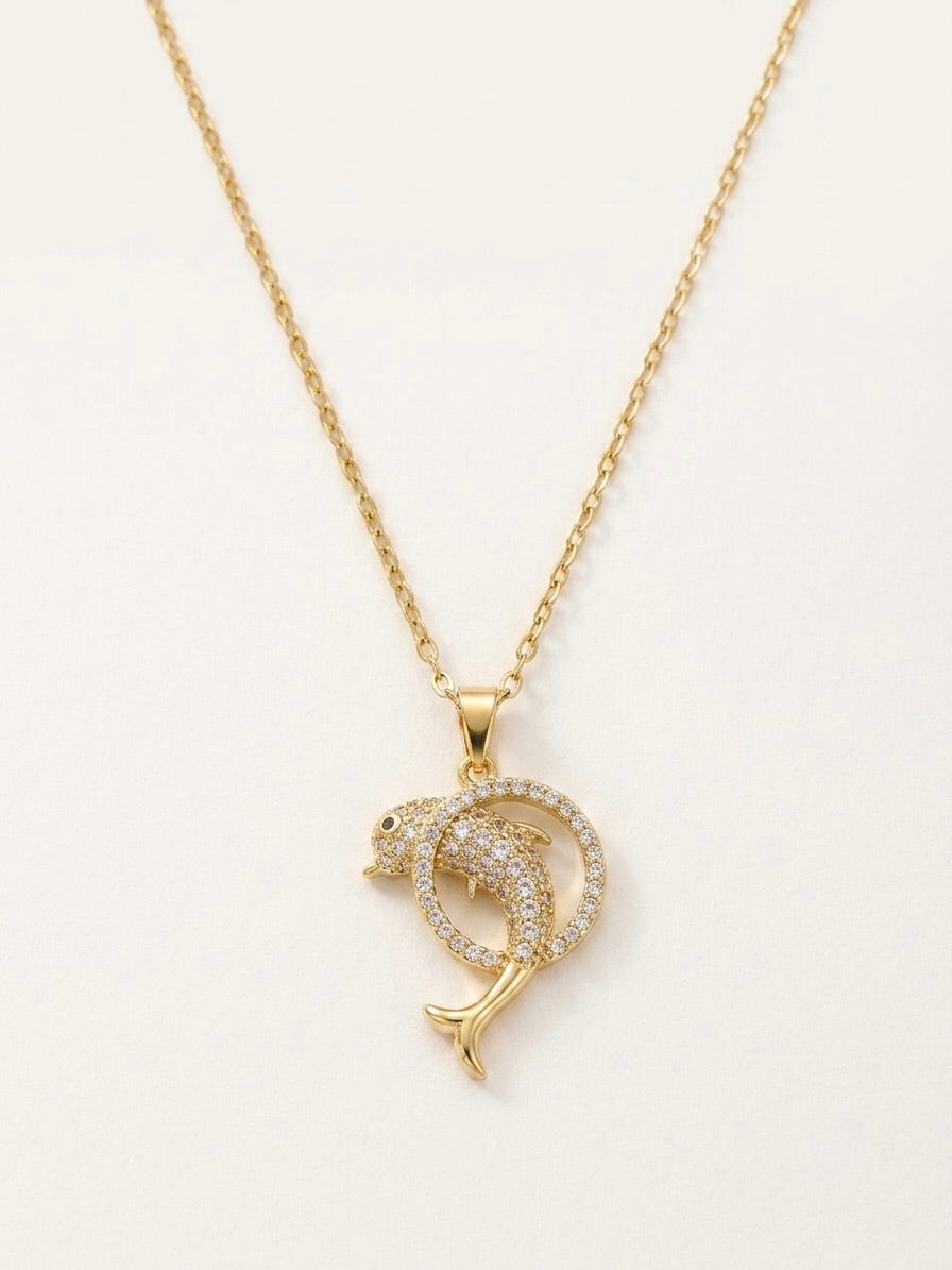 Gold dolphin pendant necklace on a white background