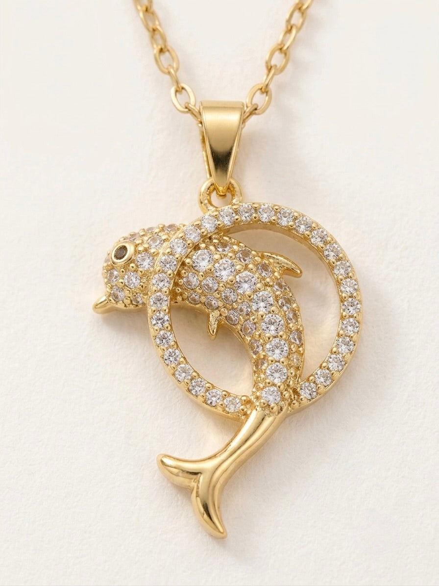 Gold dolphin pendant necklace with diamond accents on a light background