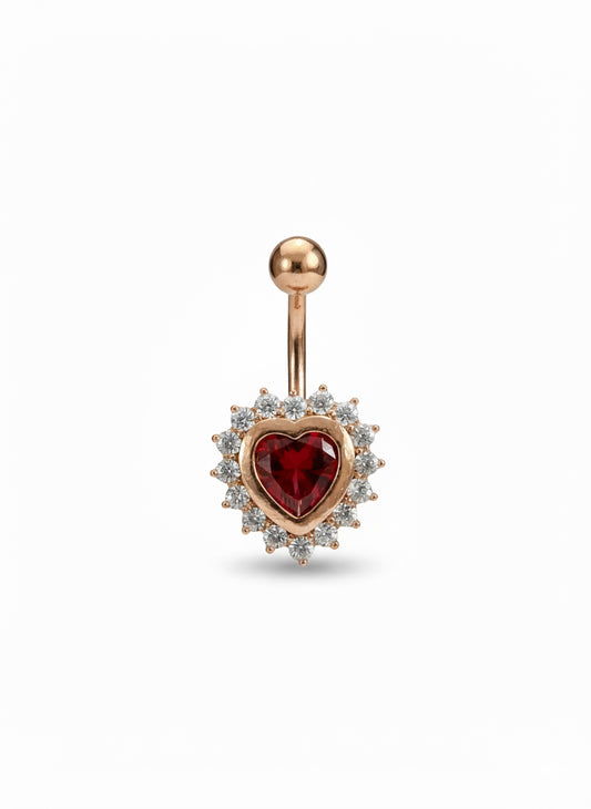 Rose gold belly button ring with a red heart gem on a white background
