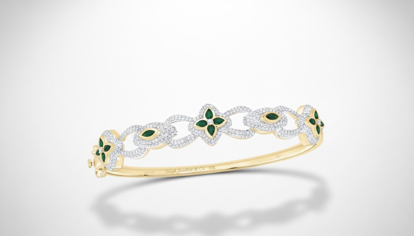 Gold bracelet with green gemstones on a light gray background