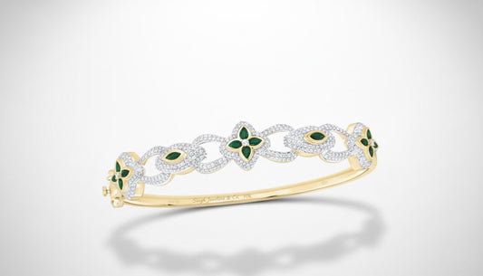 Gold bracelet with green gemstones on a light gray background