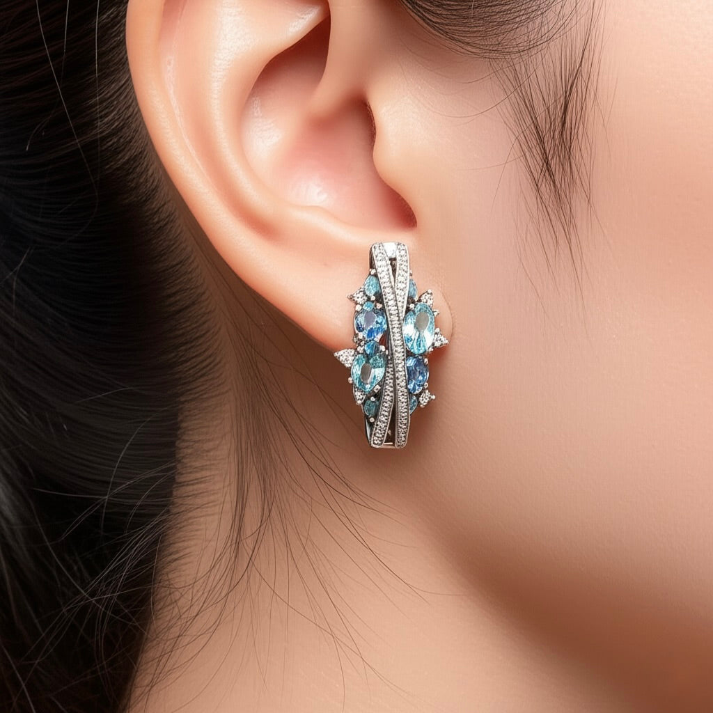 Model wearing sterling silver leverback hoop earrings with synthetic blue topaz and white sapphires