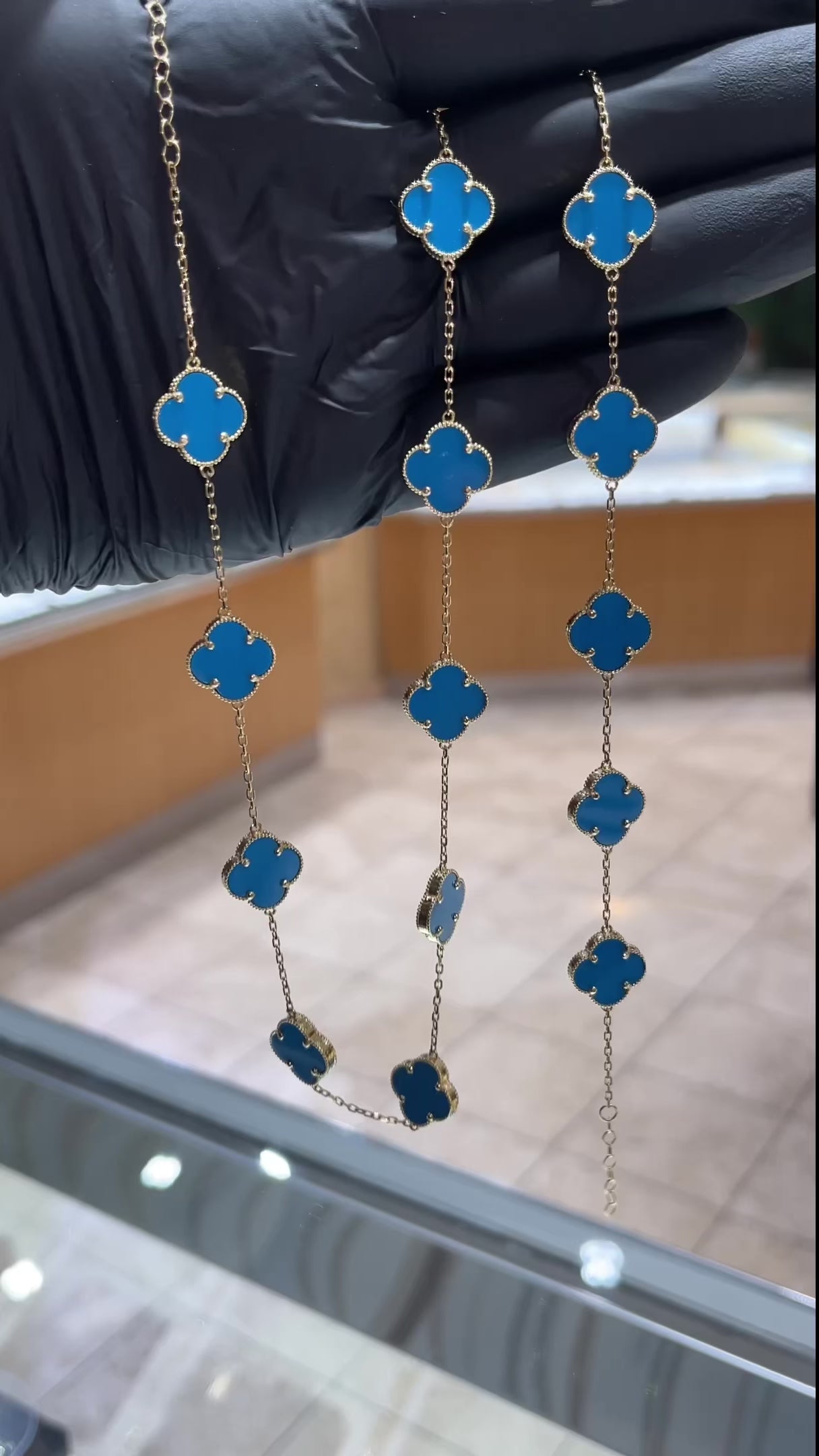 Woman wearing 10K gold necklace with sky blue clover pendant